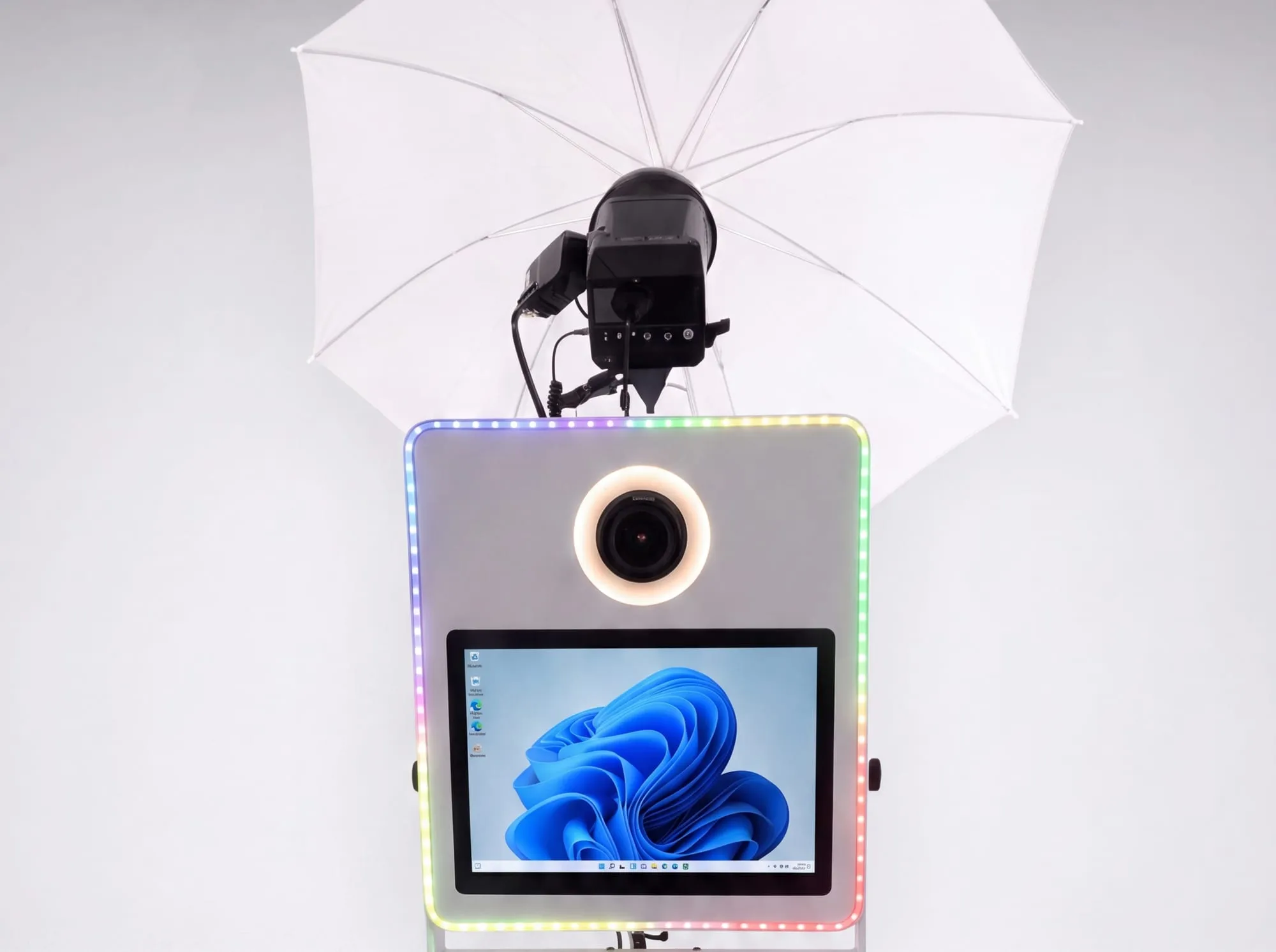 Le photobooth blanc en studio, flash de studio et parapluie diffusant déployés au-dessus du boîtier