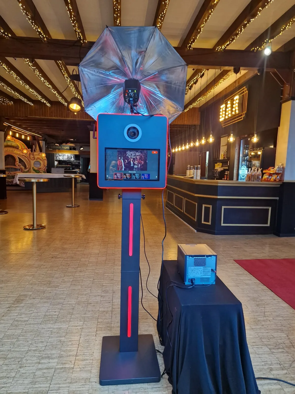 Le photobooth LED noir installé dans une salle de réception, bandeau lumineux rouge allumé